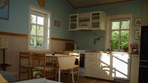 Een gezellige keuken met houten kastjes, een eettafel en stoelen.