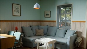 Een knus interieur met een grijze bank, een kleine witte tafel en een houten vloer.