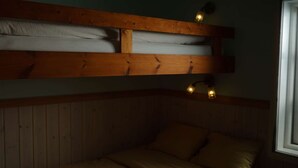 Een kamer met een stapelbed, houten lambrisering en een raam.