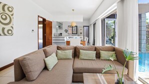 Ein modernes Wohnzimmer mit einer Eckcouch, einem Couchtisch und Blick auf einen Swimmingpool.