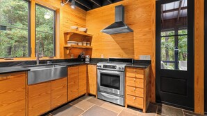 Una cucina moderna con mobili in legno, piano cottura in acciaio inossidabile e una porta nera.