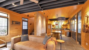 Un interno moderno con soffitto in legno, un divano, un'area da pranzo e una cucina.