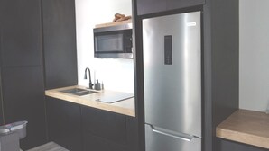 A modern kitchen with dark cabinetry, a stainless steel refrigerator, a microwave, and a wooden countertop. - Oceanfront Balcony King Bed suite steps to city center and beach Sunsets walks (Hatillo)