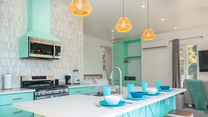Een moderne keuken met een centraal eiland, inbouwapparatuur en een blauwgroen kleurenschema.