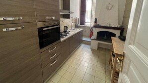 Une cuisine compacte équipée d’un four encastré, d’une plaque de cuisson et d’une machine à café.