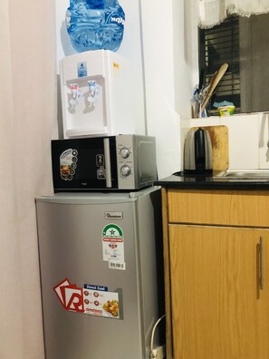 Efficient kitchen with a refrigerator, microwave, and kettle, perfect for preparing meals.