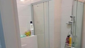 A bathroom with a glass-enclosed shower, a toilet, and a sink. - Studio in Modi'in center (Modi'in-Maccabim-Re'ut)