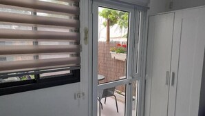 A room with a sliding glass door leading to an outdoor patio area. - Studio in Modi'in center (Modi'in-Maccabim-Re'ut)