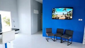 Una sala de estar moderna con una pared azul de acento, un televisor de pantalla plana y tres sillones grises.