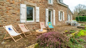 A stone building with a patio area featuring lounge chairs and a table.