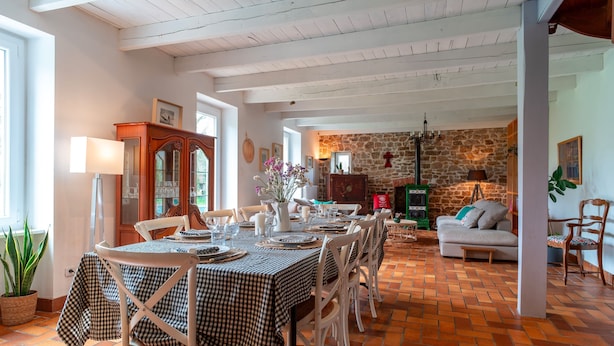 A dining area with a checkered tablecloth, white chairs, and a stone wall in the background.