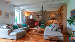 A cozy living room with two sofas, a coffee table, and a stone wall.