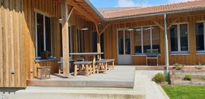 A wooden building with a covered patio area, large windows, and outdoor seating. - La Cabane - Maison moderne proche du port de Dahouët (Pléneuf-Val-André)
