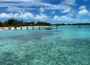 A clear turquoise sea with a sandy beach and wooden structures. - The Pink @ Hoopers Bay Beach (Hoopers Bay)