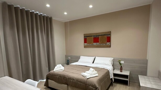Una habitación de hotel moderna con una cama grande, un escritorio y una mesita de noche.