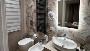 Un baño moderno con dos bidés, un espejo grande y un tocador con lavabo.