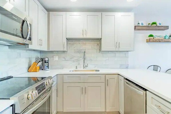 Efficient kitchen with a double sink, oven, and stainless steel range hood.