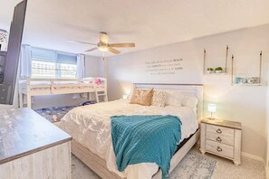 Cozy retreat with a neatly made bed, desk area, and wall-mounted shelf.