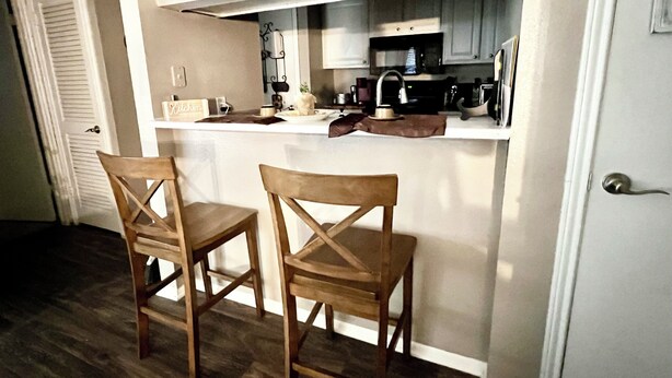A small kitchen with two wooden chairs, a kitchen sign, and a microwave.