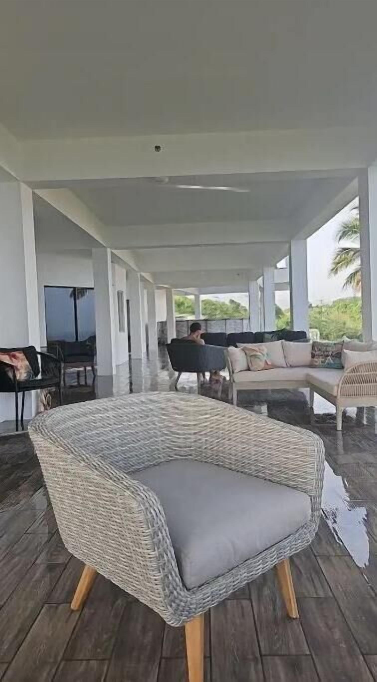 A covered outdoor seating area with wicker furniture and a view of the outdoors.