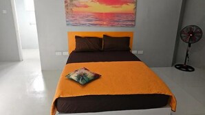 Ein Schlafzimmer mit einem Bett, einem Wandventilator und einem Sonnenuntergangsbild.
