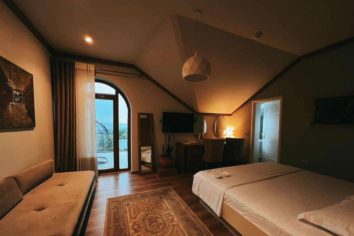 Un dormitorio acogedor con cama, sofá, escritorio y vistas al exterior.