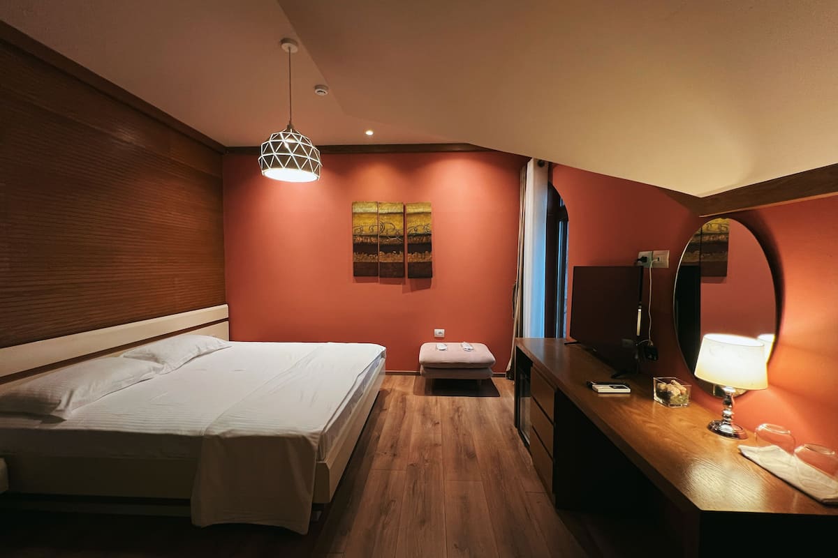 Una habitación de hotel con cama, mesita de noche, lámpara y un cuadro en la pared.