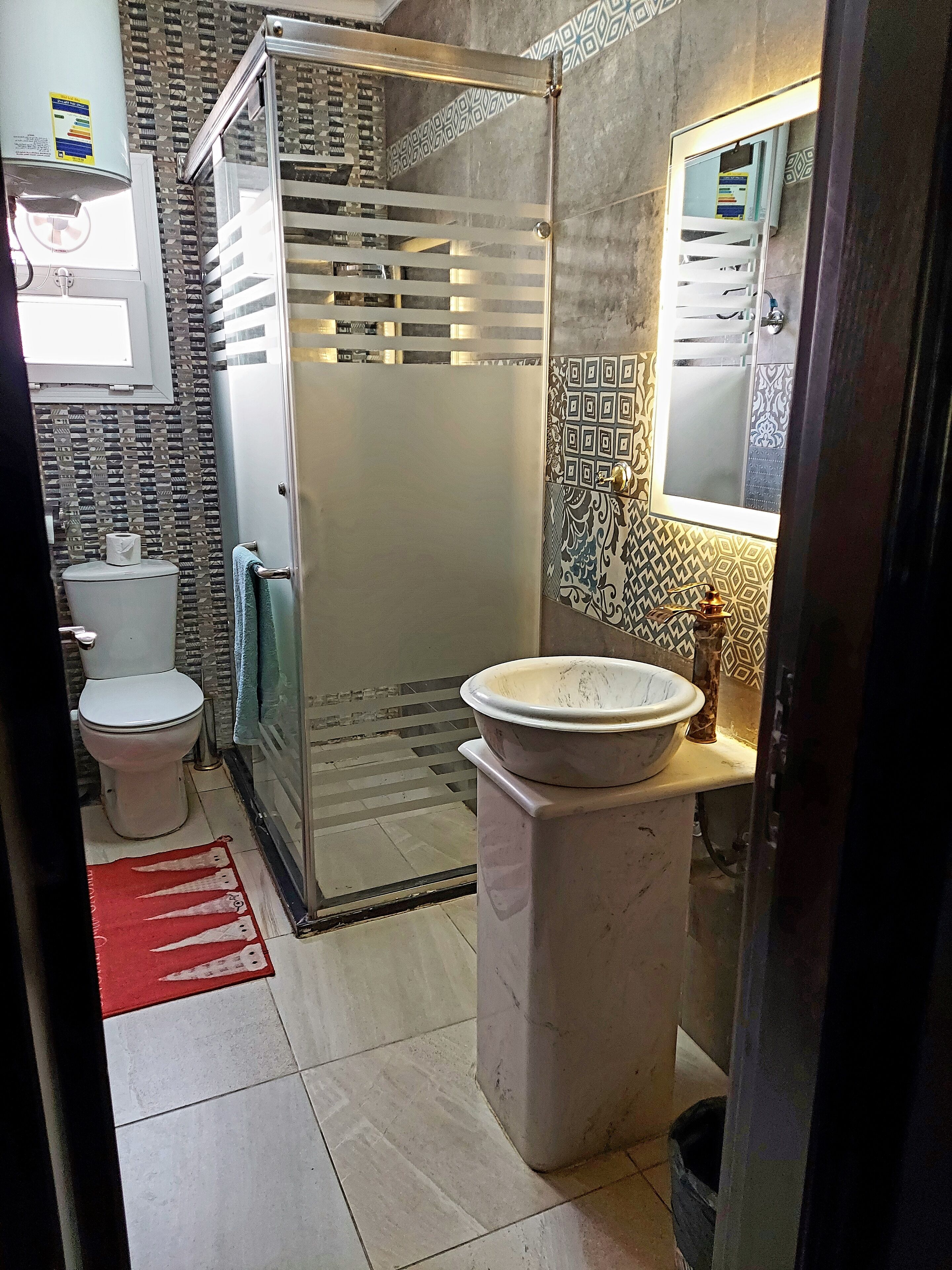 A bathroom with a toilet, a shower enclosure, a sink, and a mirror.
