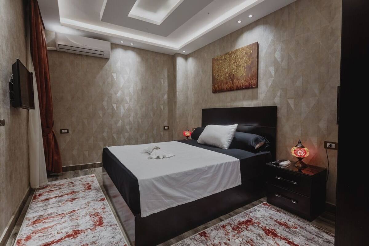 Un dormitorio moderno con una cama grande, una mesita de noche con lámpara y un aplique de techo.