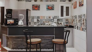 A modern kitchen with a black countertop, two bar stools, and a variety of decorative tiles on the walls. - Pyramids planet hotel (Giza)
