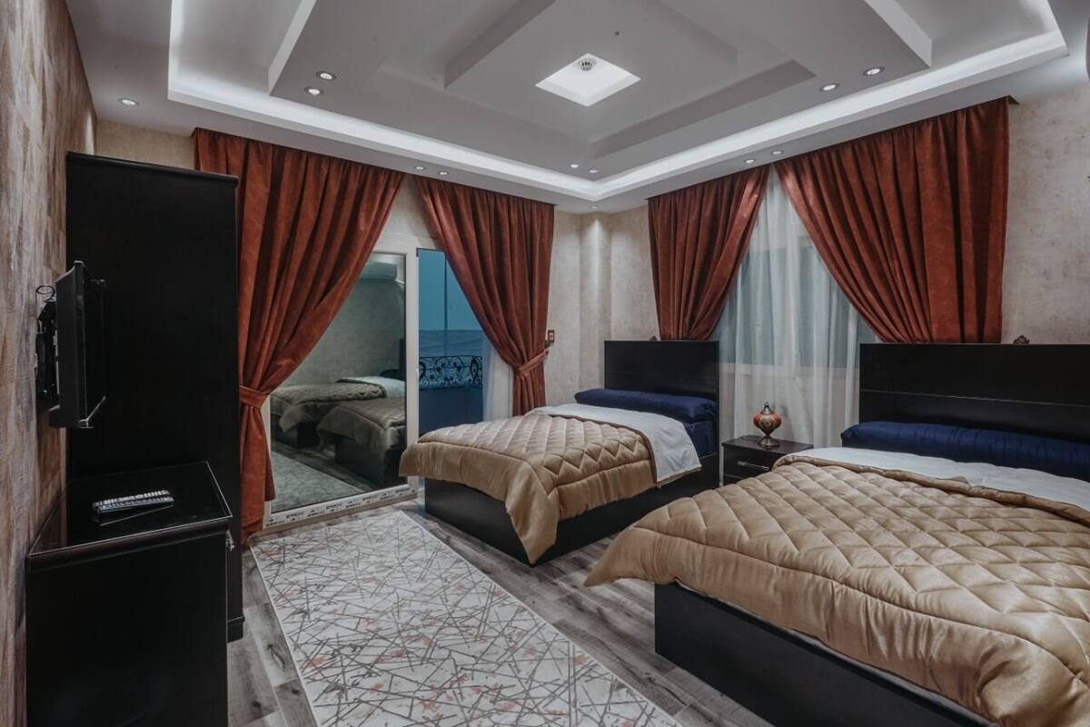 Habitación de hotel con dos camas, televisión y un amplio ventanal con cortinas.