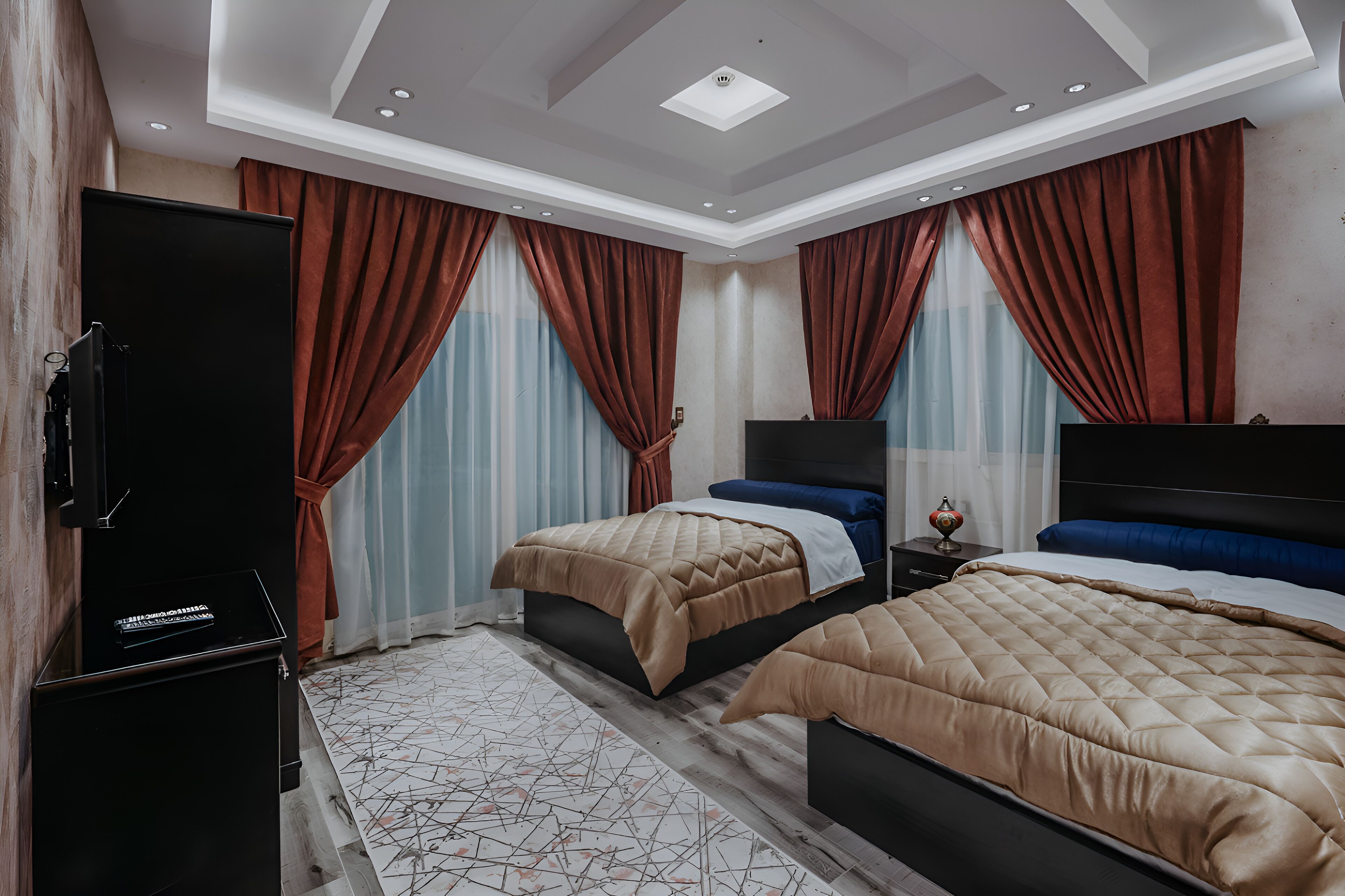 Habitación de hotel con dos camas, un televisor de pantalla plana y un minibar.