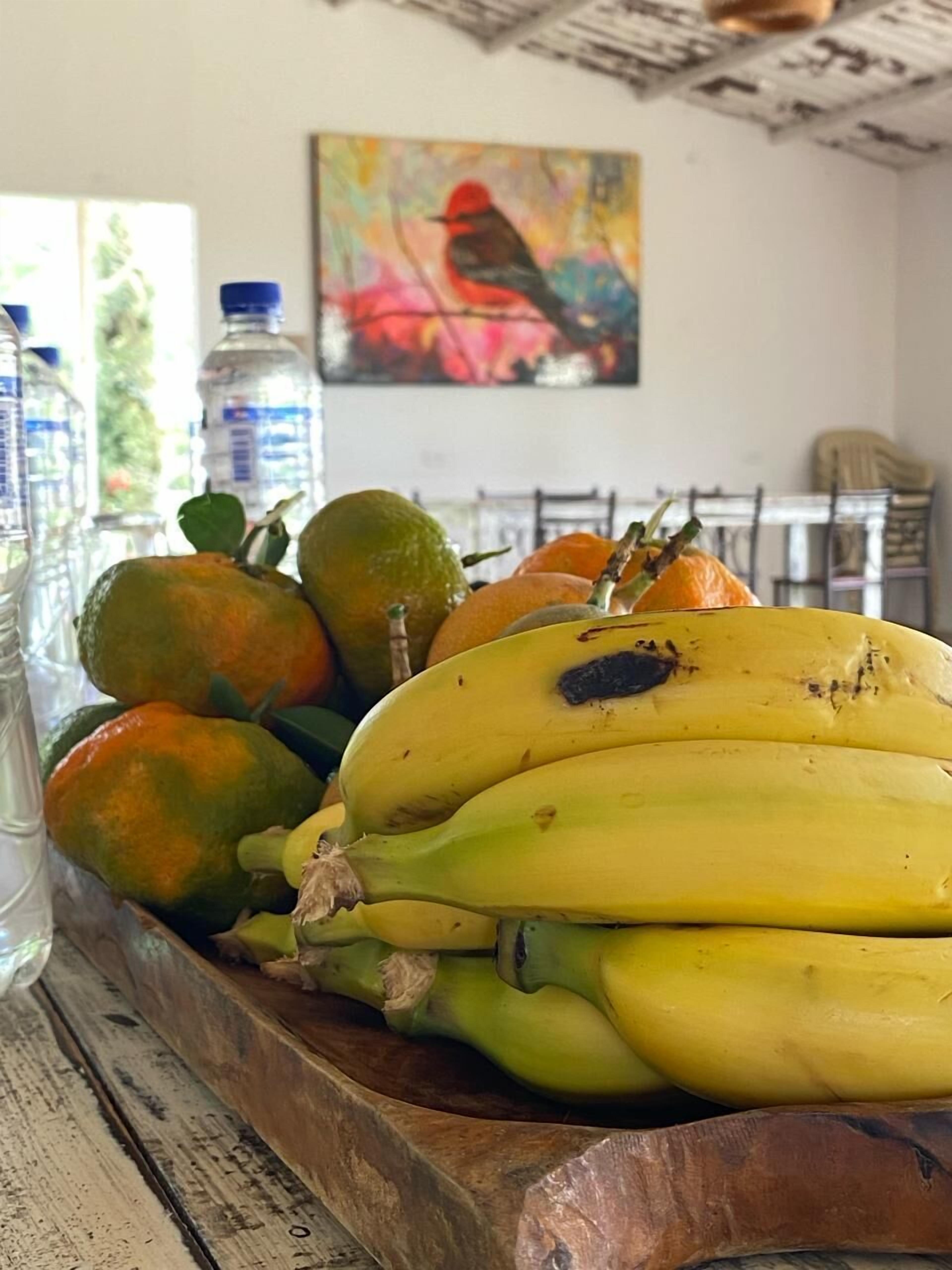 A wooden tray with bananas, limes, and water bottles on a table.
