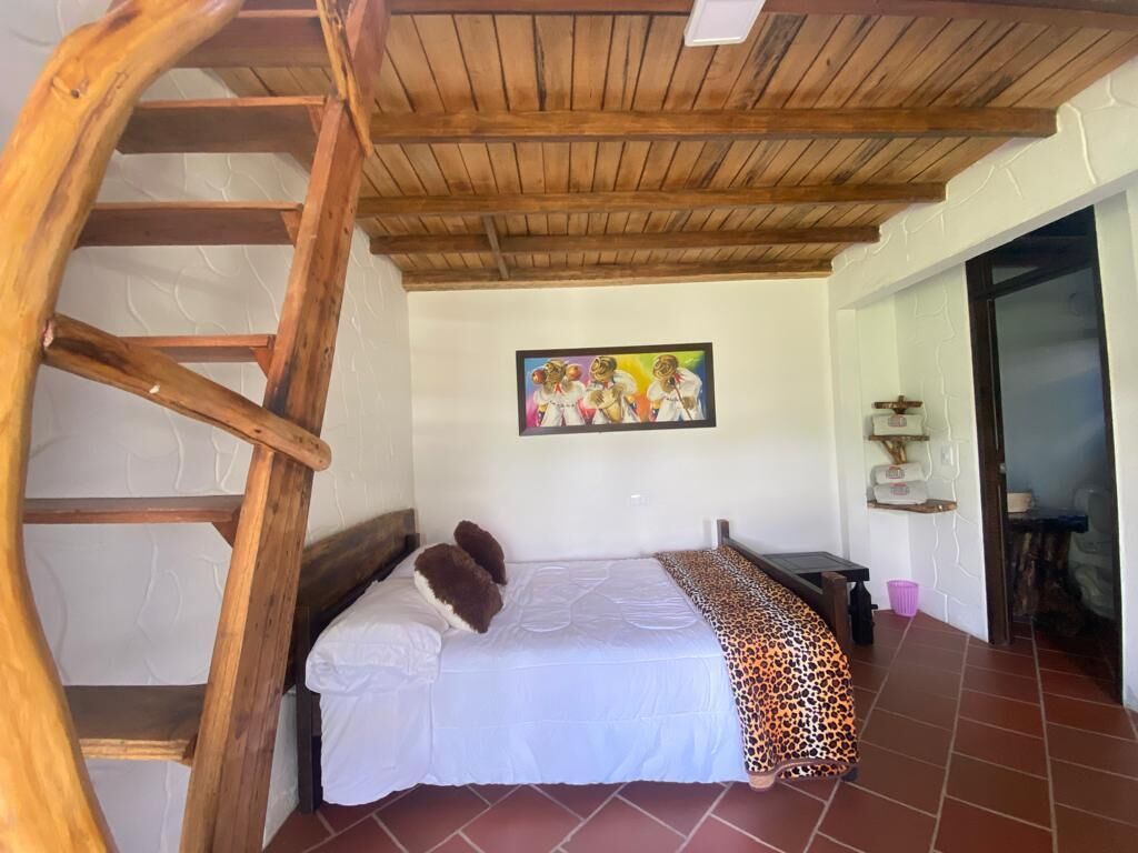 A bedroom with a wooden ladder, a bed with white bedding, a leopard print blanket, and a colorful painting on the wall.