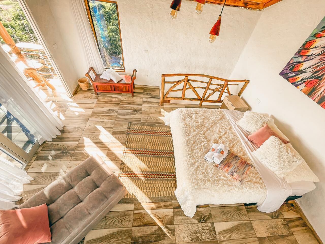 A spacious living area with a wooden floor, a sofa, a chair, and a wooden bench.