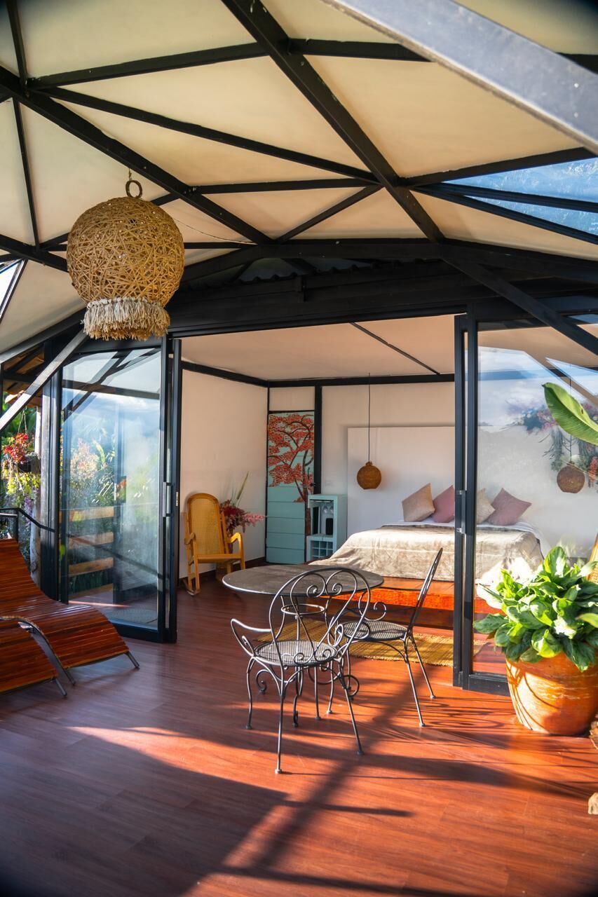 Ein modernes Interieur mit Bett, Sitzecke und Blick durch Glastüren.