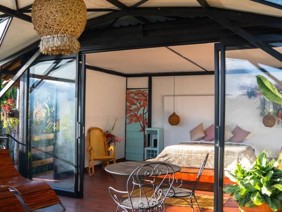 A modern interior with a bed, seating area, and a view through glass doors.