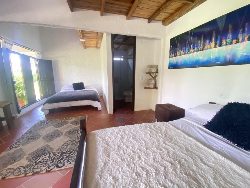 Ein Schlafzimmer mit zwei Betten, einem großen Fenster und einem Bild an der Wand.