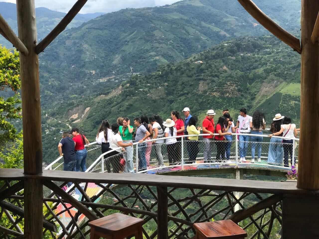 Un grupo de personas en una pasarela de madera con vistas a un paisaje montañoso.