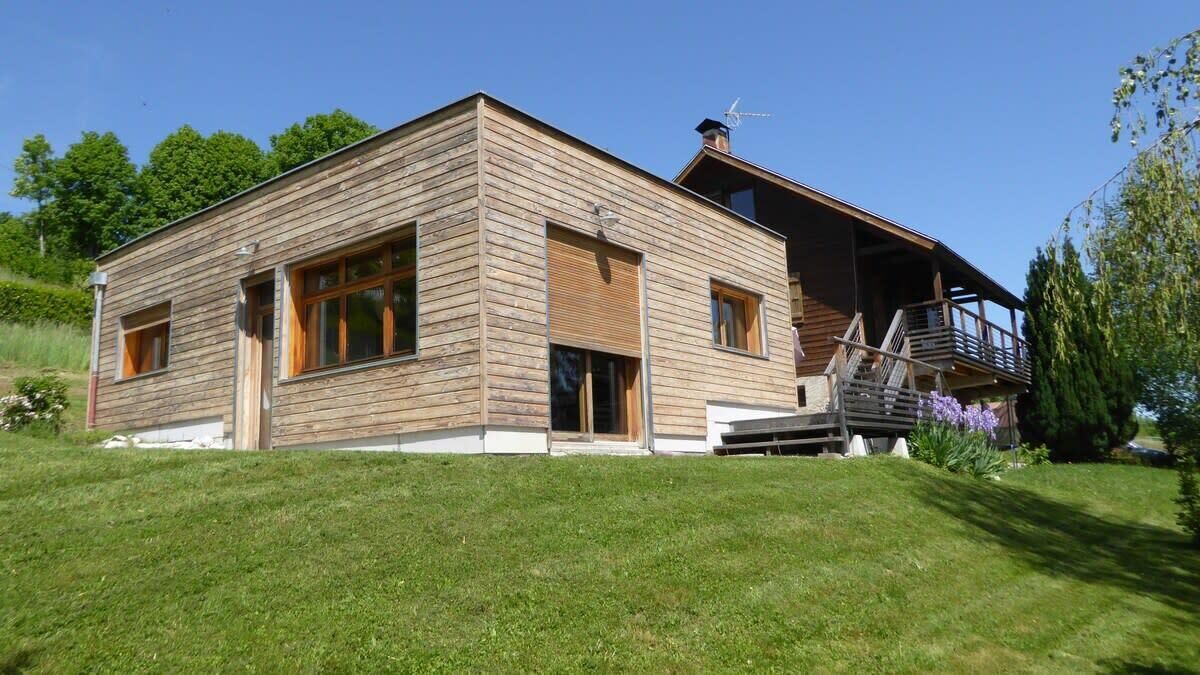 Et moderne træhus med en overdækket veranda og en trappe til en øvre etage.