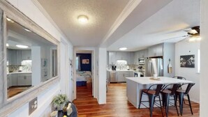 A modern kitchen with a central island, wooden flooring, and a dining area with bar stools.