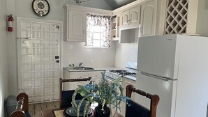 Une cuisine avec des meubles blancs, une cuisinière et un réfrigérateur.