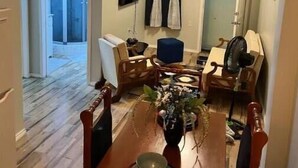 Un coin repas avec une table en bois, des chaises, un vase de fleurs et un téléviseur fixé au mur.