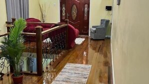 Un vaste espace de vie doté d’un plancher en bois, d’un canapé rouge, d’un fauteuil gris et d’une rambarde décorative.