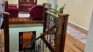 Un vaste espace de vie agrémenté d’un escalier en bois, d’un canapé rouge et d’un téléviseur fixé au mur.