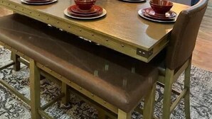 Un coin repas avec une table en bois, des bols rouges et un banc.
