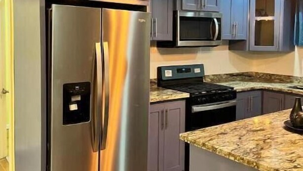 Une cuisine équipée d’un réfrigérateur en acier inoxydable, d’un four à micro-ondes et d’une cuisinière.