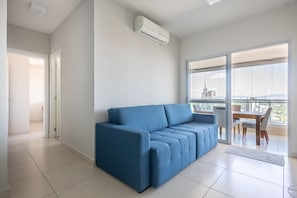 Relax in this stylish living room with a sofa, sliding glass door to a balcony, and air conditioning for a comfortable stay.