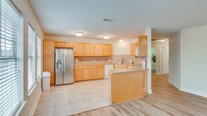 A modern kitchen with wooden cabinets, a built-in refrigerator, and a central island.