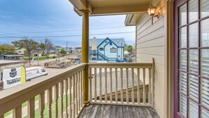 A balcony with a view of a blue house and a van parked on the street.